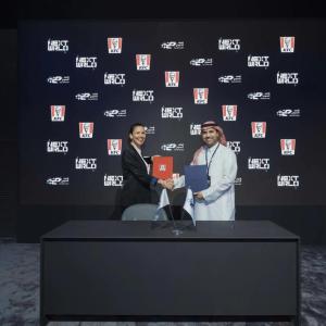 Representatives from SEF and KFC shake hands behind a black desk