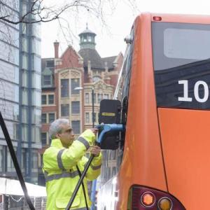 A person connecting an electric truck to a charging station