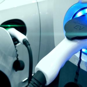 A white electric vehicle, plugged in.