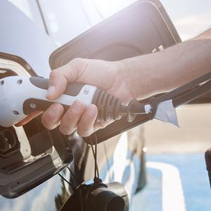 A hand holding a plug to an electric vehicle.
