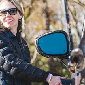 A person smiling towards the side while charging an electric vehicle.