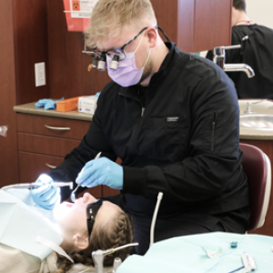 A dental student examines a patient's teeth.