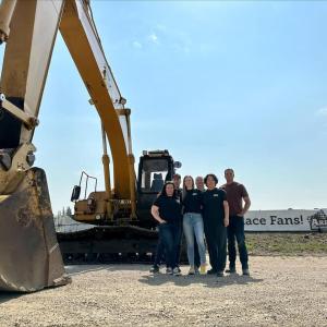 Group of people next to a large piece of construction equipment