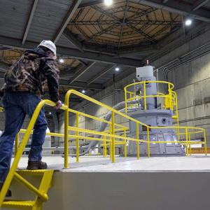 a worker climbing stairs that lead to a walkway over a large turbine