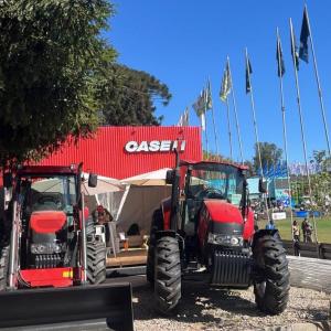 Two farming machines in front of a small Case IH building.