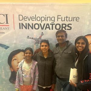 A family group posed in front of a CACI banner