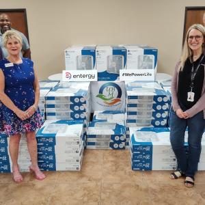 A group posed by stacks of fans in boxes.