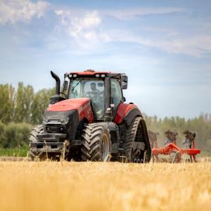 A person in a farming machine, tilling the soil in a field.