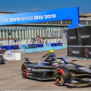 "Net zero since day zero" banner over a race track with cars going by.