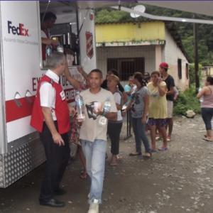 a line of people near a van handing out food and water