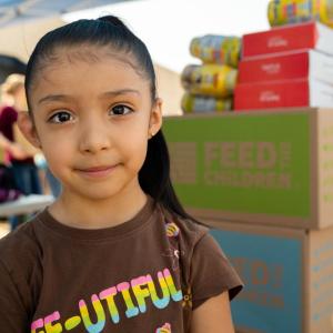 Child with boxes of food stacked behind her