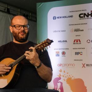 man in a black t-shirt and glasses playing a mandolin