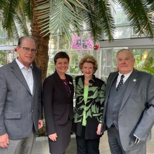 Group of four people, a palm tree behind them.