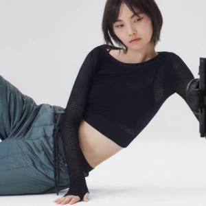 A model sitting on their side on the floor, a camera to the right