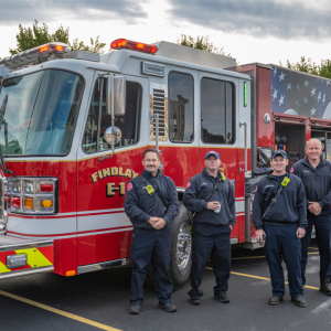A group of firefighters in front of a fire truck "Findlay Fire" on the side