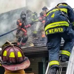 Firefighters climbing onto smoking roof