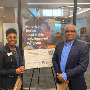 Two people stand beside a poster "American Indian Leadership Development Program."