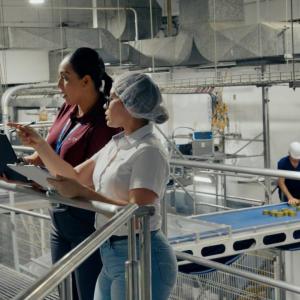 Two people looking at a laptop in an industrial plant.