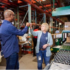 Two employees fist bump in a fulfillment center