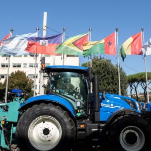 Blue tractor parked outside in front of different flags