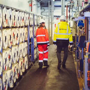 Two people in high-vis gear walking through a plant