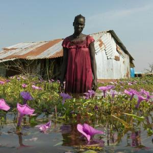 Portrait of Nya Jol outside her flooded home. "My husband goes to market often to find work, while I remain here to look after the children. I hope he finds some casual work soon so we can buy vegetables to eat with the fish we catch" says Nya.