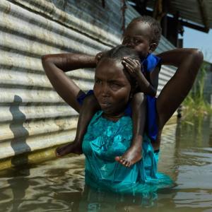Aweng Thang wades through water with her daughter in Old Fangak.