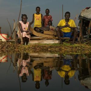 Adit Kak and her family sit on their floating home. Although they are able to catch fish, they live in isolaton since the flood water ook their old home in October. " We lost everything in the floods but we do not want to leave this place. We have lived here all our lives and call this place home" says Adit.