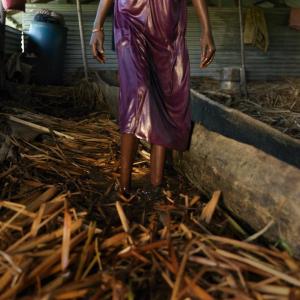 Nyayiena at home in the background is an abandoned classroom. She is living on a floating pontoon. By tightly packing many layers of grass on top of one another, the floor becomes a floating floor that will rise and fall with the flood water.