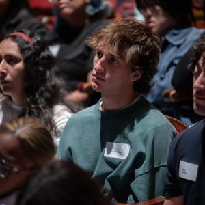 Close-up of attendees seated in theater rows listening during a panel discussion.