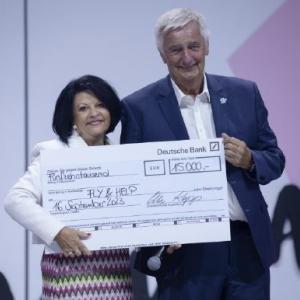 Two people posing with a large check made to Fly & Help.