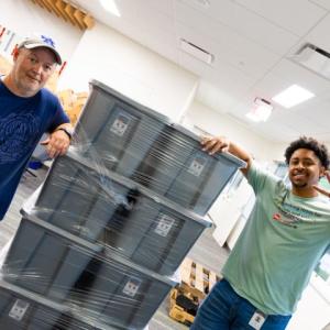 Two volunteers next to large boxes