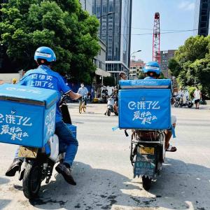 Two matching people on motorbikes, blue containers on the back.