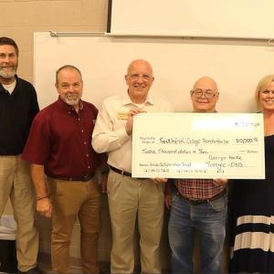 Five people holding an oversized check