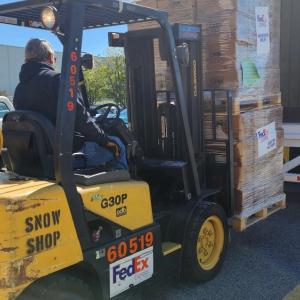 a person loads an open trailer using a forklift