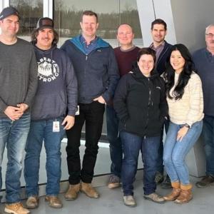 A team of people in a group pose outside a building.
