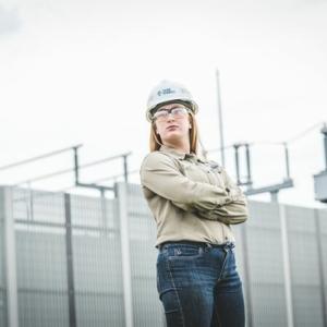 A worker in a hard hat, standing with crossed arms