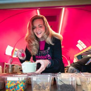 A person putting toppings on a cup of froyo in a pick trailer.