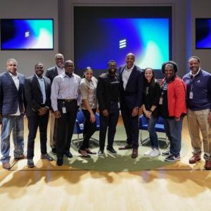 A team of people on a stage with three digital screens behind them