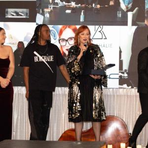 A presenter with a microphone, three others to their sides.