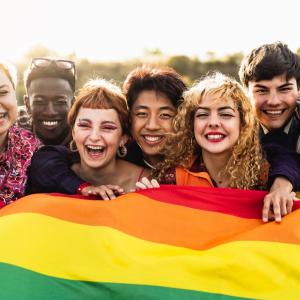 Group of individuals holding a rainbow flag.