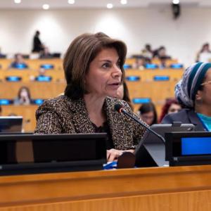  IOC Member, Laura Chinchilla, sitting at a desk and speaking into microphone