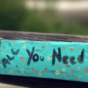 board painted with the words "all you need is love"