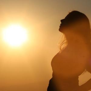 woman leans back in silhouette against a strong orange sun