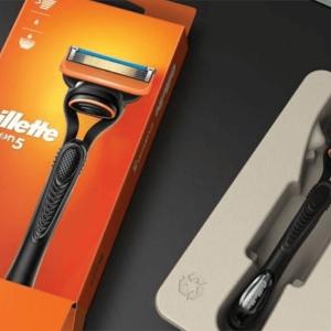 An orange box with Gillette logo and picture on a razor, on the right the product in a cardboard holding box.