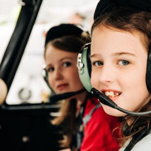 two children sitting in a plane wearing headphones