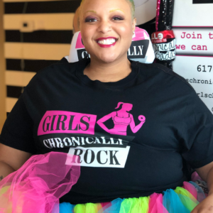 A person in a colorful tutu and black tshirt with "Girls Chronically Rock".