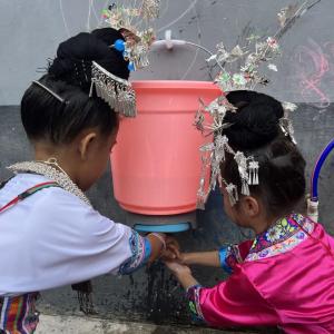 girls in traditional dress washing their hands
