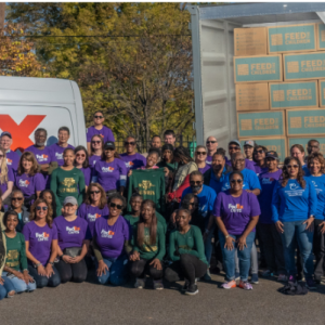 A large group of volunteers posed in front of a FedEx truck and trailer.