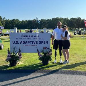 golfers posing next to sign